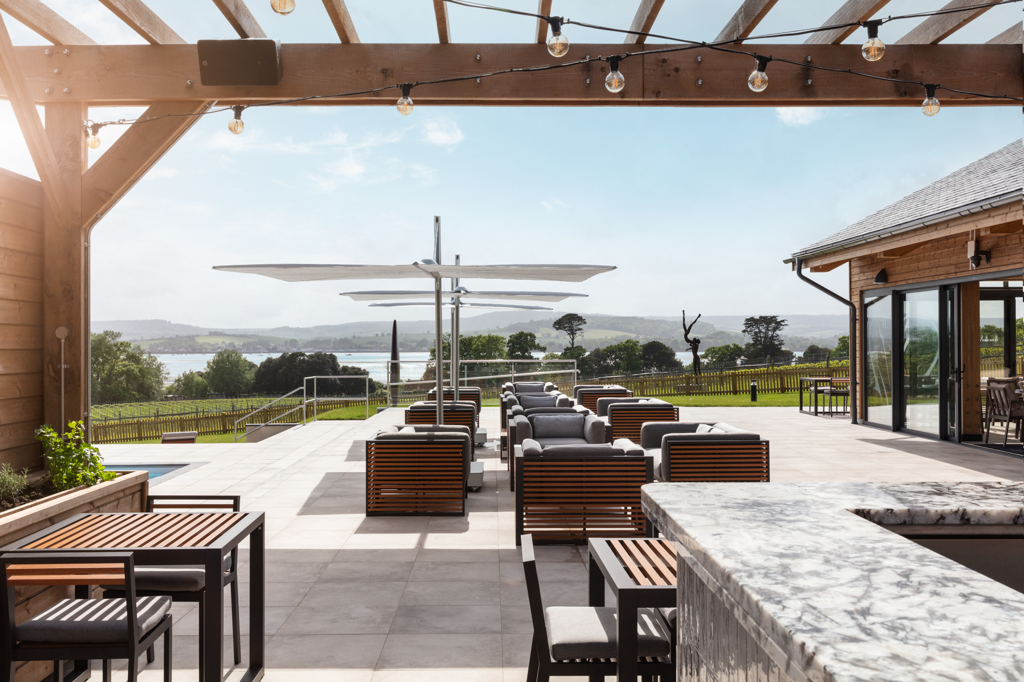 Table and chairs outside the Pool House Restaurant bathed in sunlight and overlooking the estuary