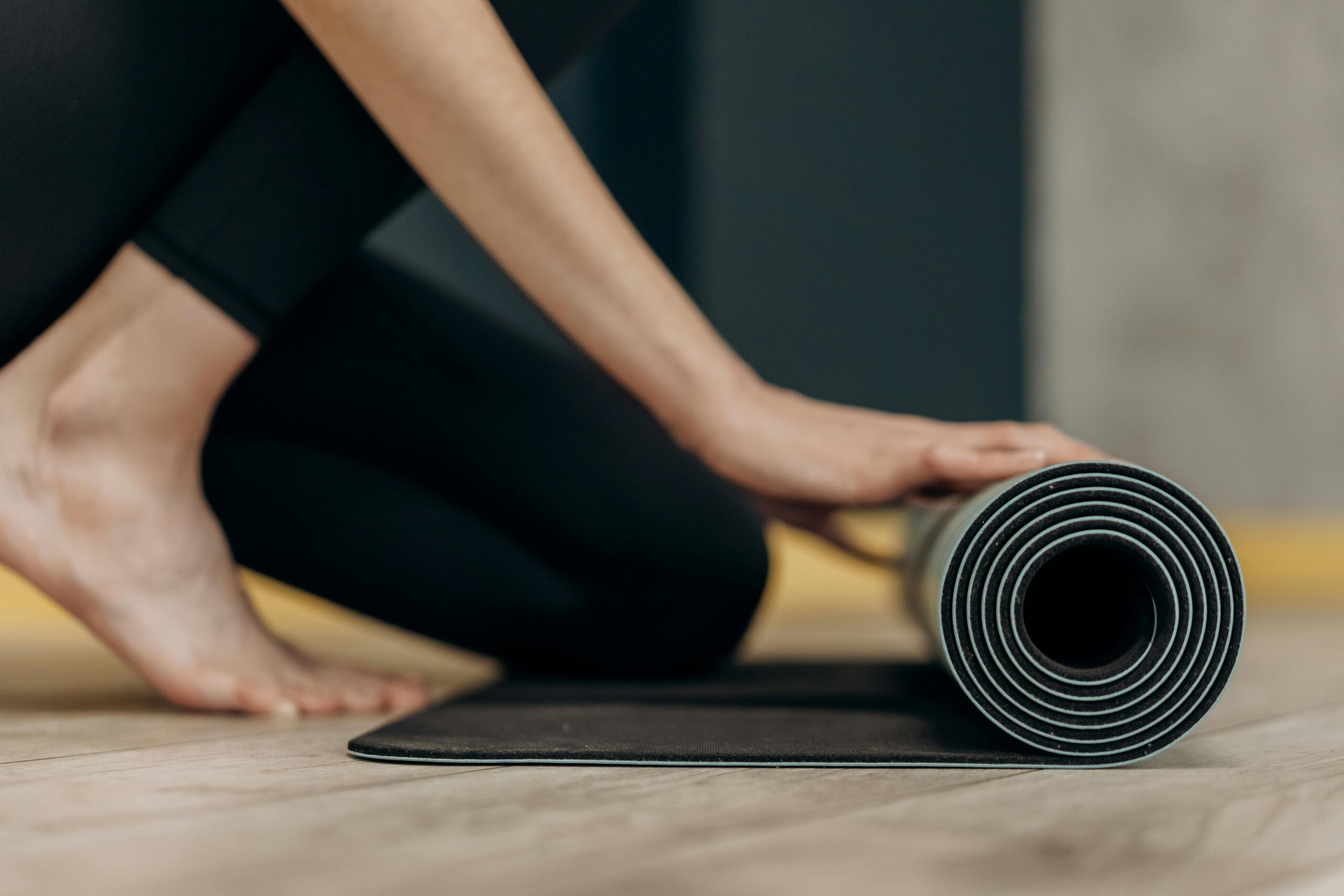 person rolling out yoga mat in a yoga studio