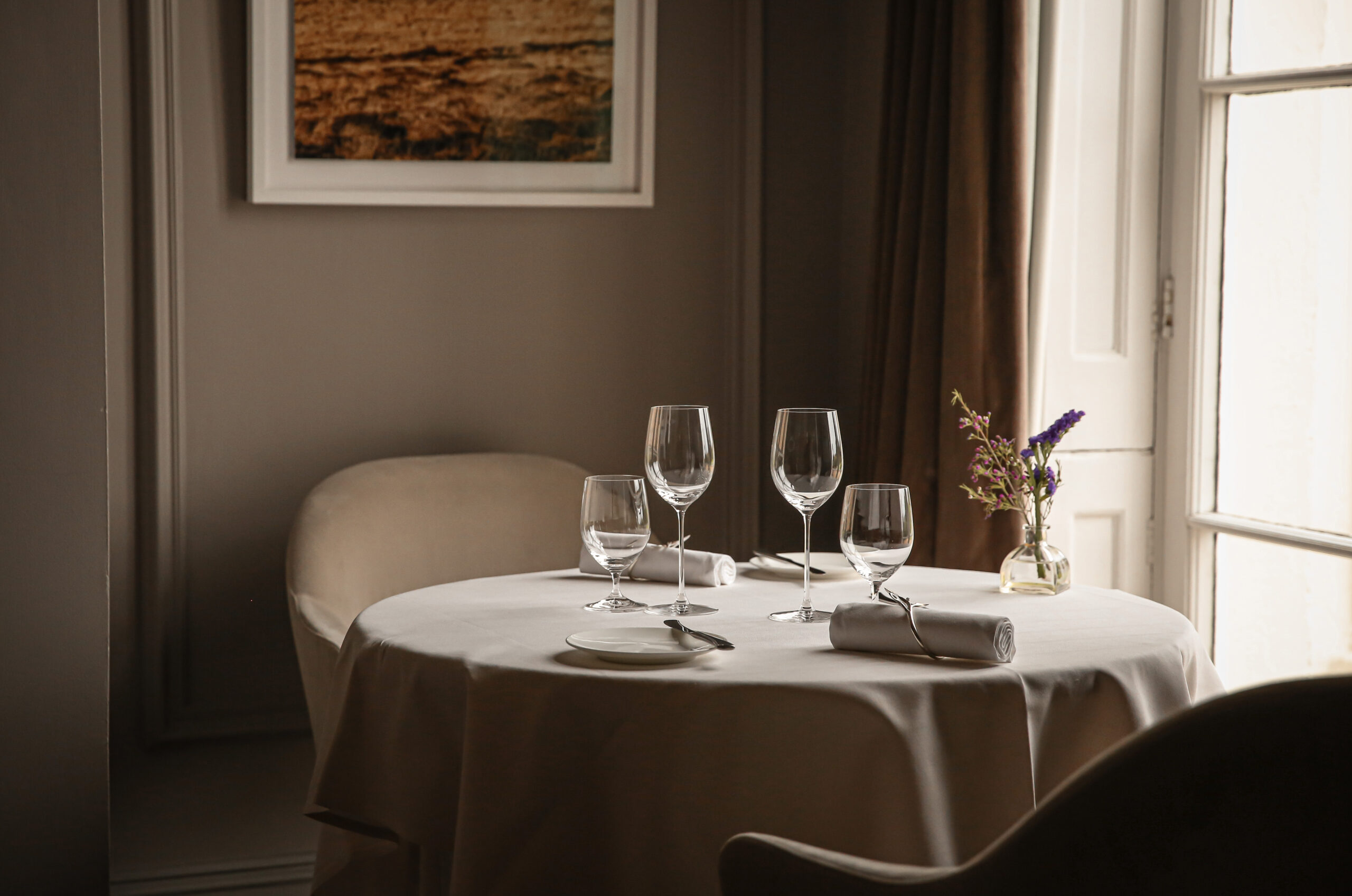 Fine dining restaurant at Lympstone Manor with table set for lunch and artwork in the background